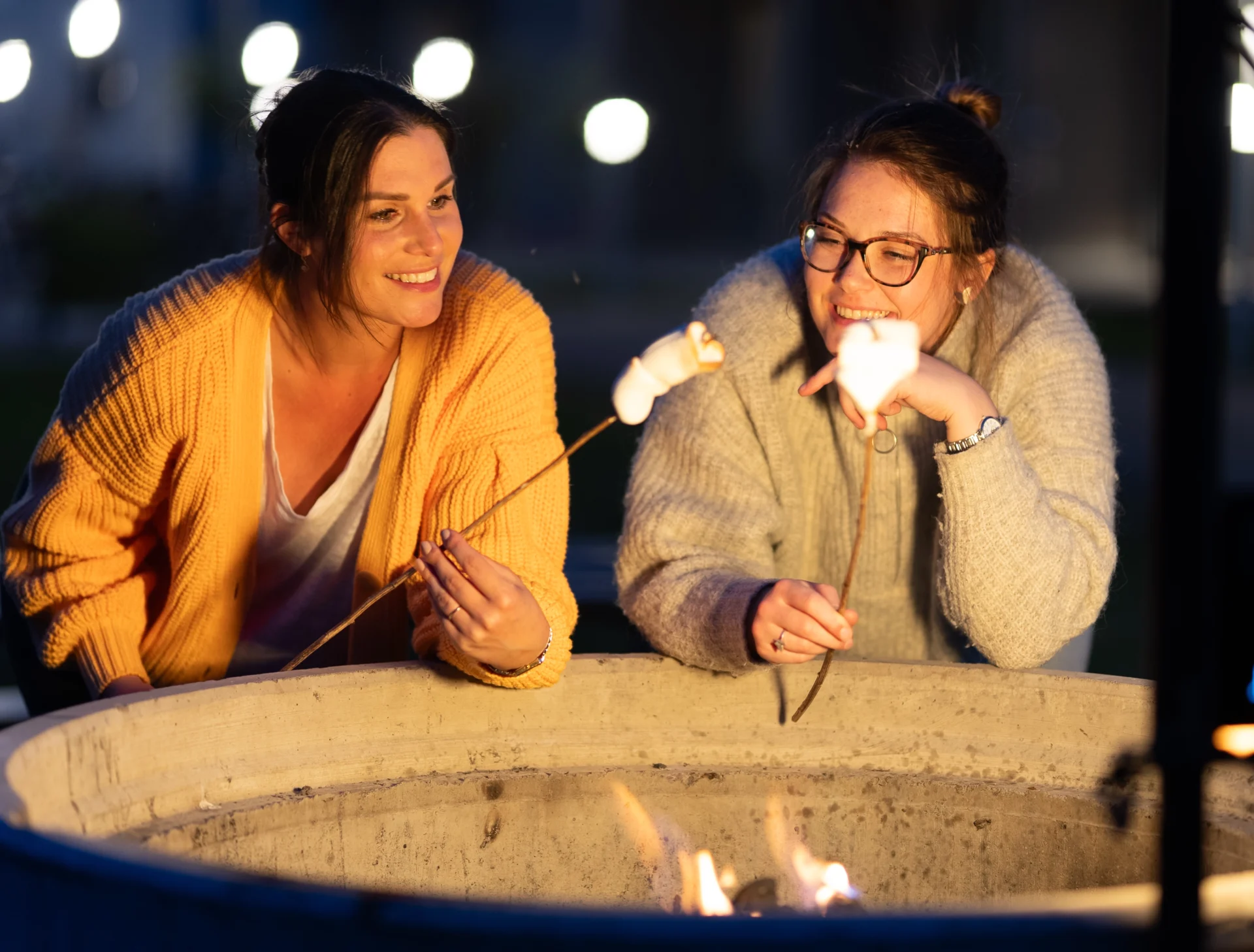 Två studenter grillar marshmallows vid en av grillplatserna på Campus Hills.