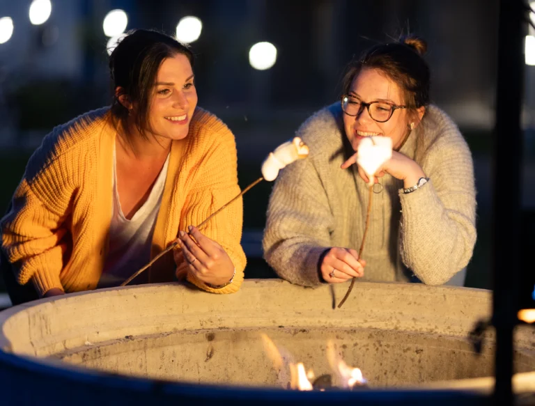 Två studenter grillar marshmallows vid en av grillplatserna på Campus Hills.